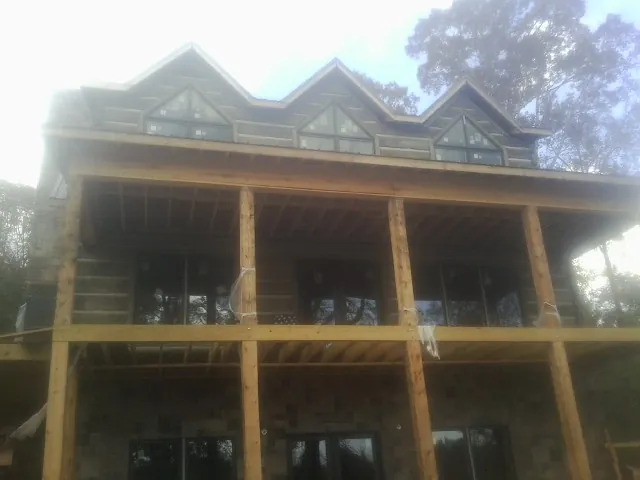 Dormers and porch framing on a large log home under construction — Roof Coating work by our crew in Monticello