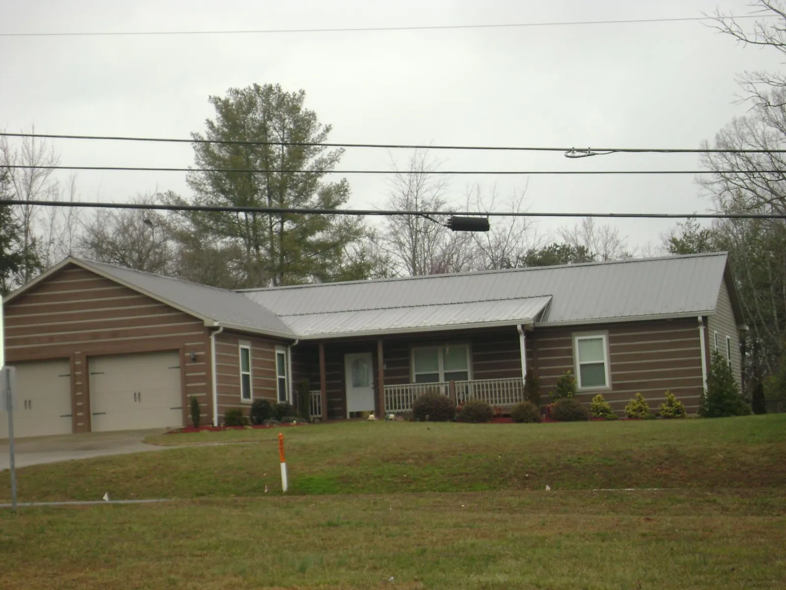 Gray metal roof on a log sided ranch home with a front porch in Monticello